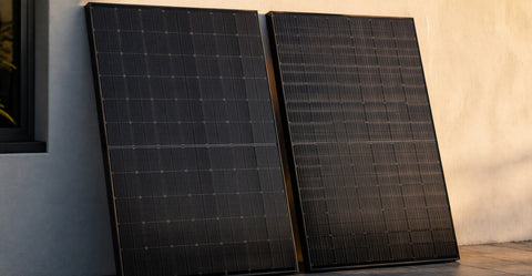 Dos paneles solares premium todo negro inclinados lado a lado para comparación