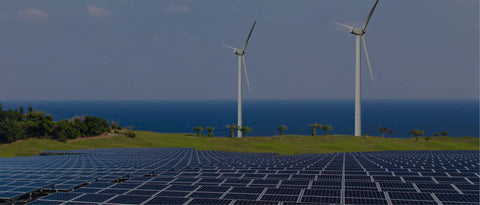 Solar panels and wind turbines on a green field by the ocean, renewable energy landscape