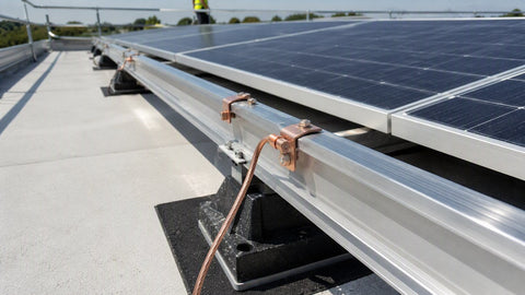 Arreglo solar comercial de techo plano con terminales de cobre uniendo los rieles de aluminio