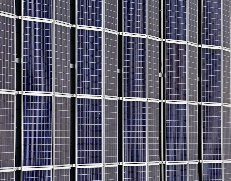 Close-up of multiple blue photovoltaic solar panels in a clean, grid-like arrangement