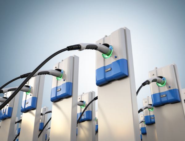 Electric vehicle charging stations with cables plugged in against a clear sky.