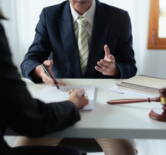 Two professionals in a business setting with a gavel on a table.