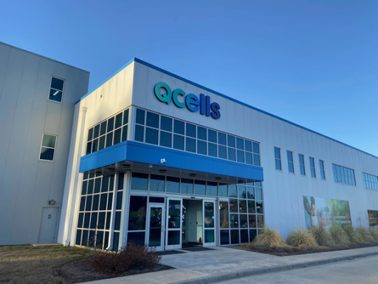Qcells building with blue and white facade under clear sky