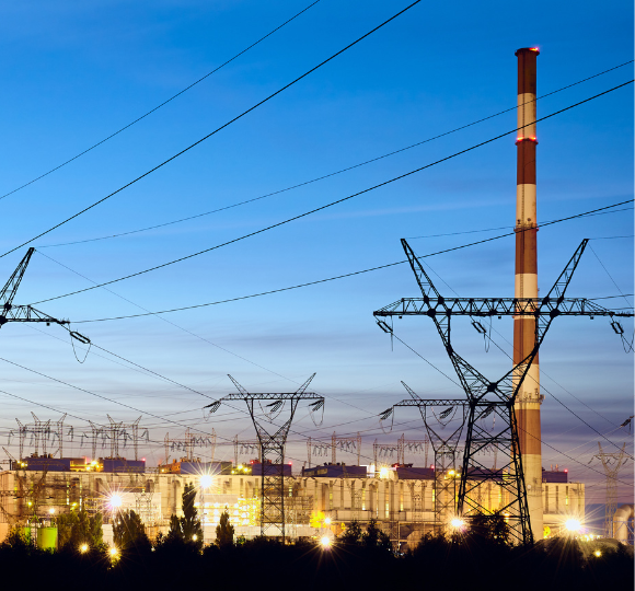 Power plant with smokestack and electrical transmission lines against a blue sky.