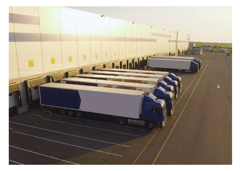 Row of trucks parked in a large warehouse or storage facility.