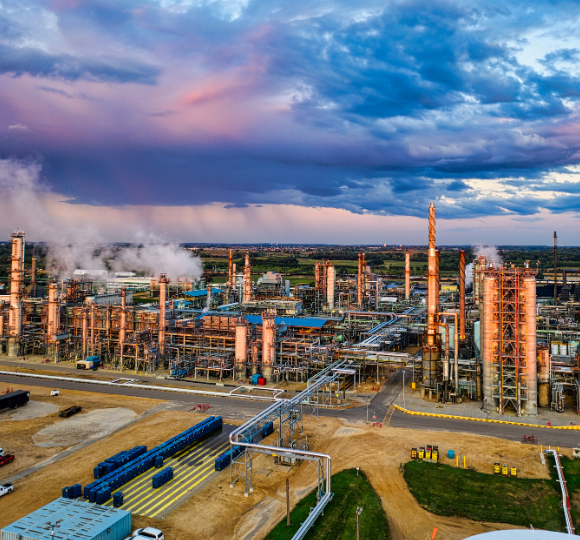 Industrial complex with tall structures and pipes under a dramatic sky.
