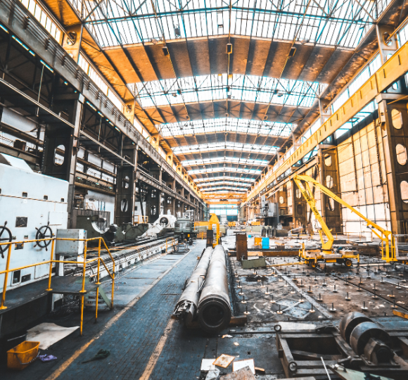 Large industrial warehouse with high ceilings and large pipes on the floor