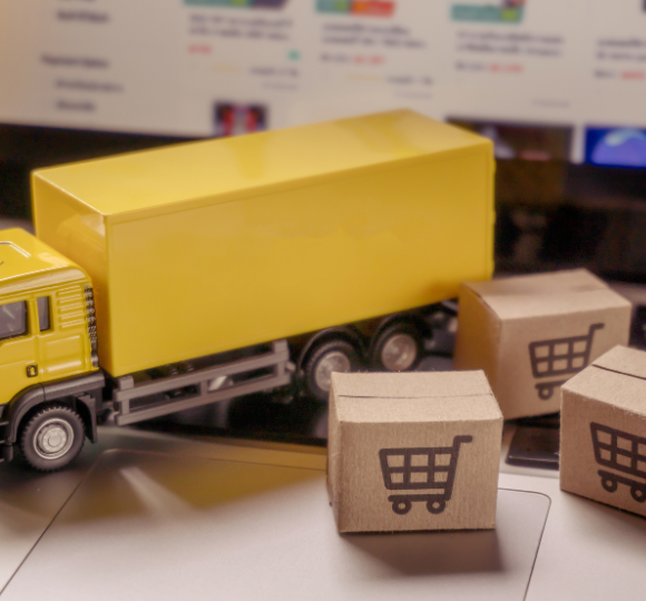 Toy truck with cardboard boxes featuring shopping cart symbols on a blurred background